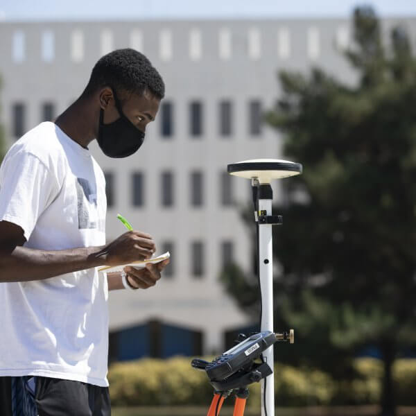 a man outside using an engineering survey tool