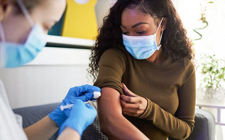 a woman being vaccinated wearing a mask