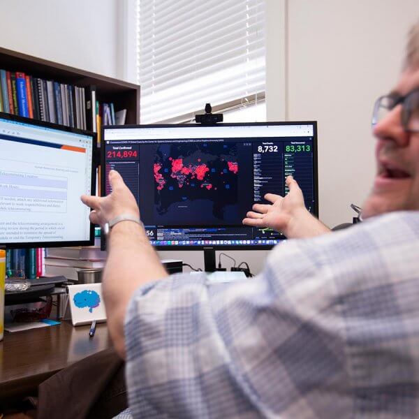 Sean Walker gestures at computer screen with Coronavirus map displayed