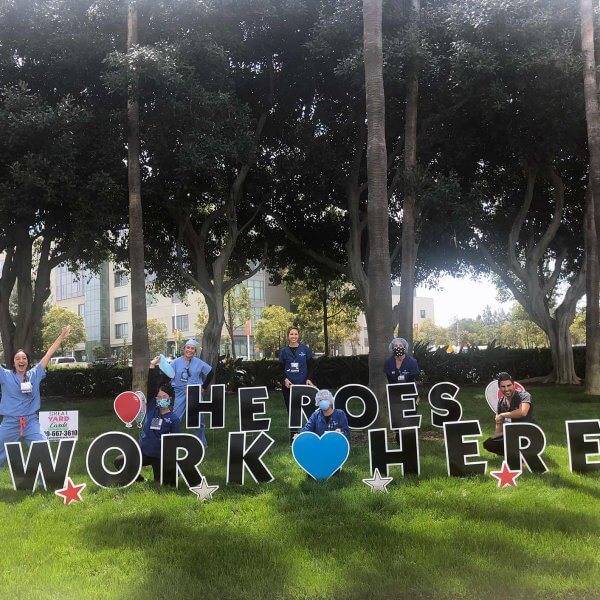 Group of health care workers in front of a sign that reads "Heros Work Here"