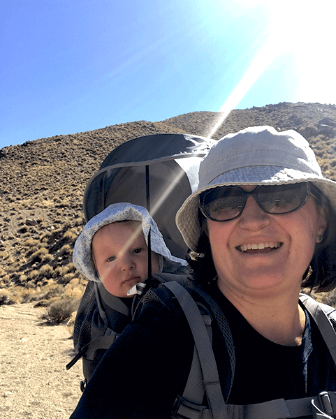 A woman in desert with a baby in a backpack