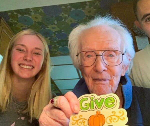 elderly man wearing glasses smiling and with a young woman and man/