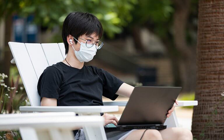 a man wearing eyeglasses working on a laptop